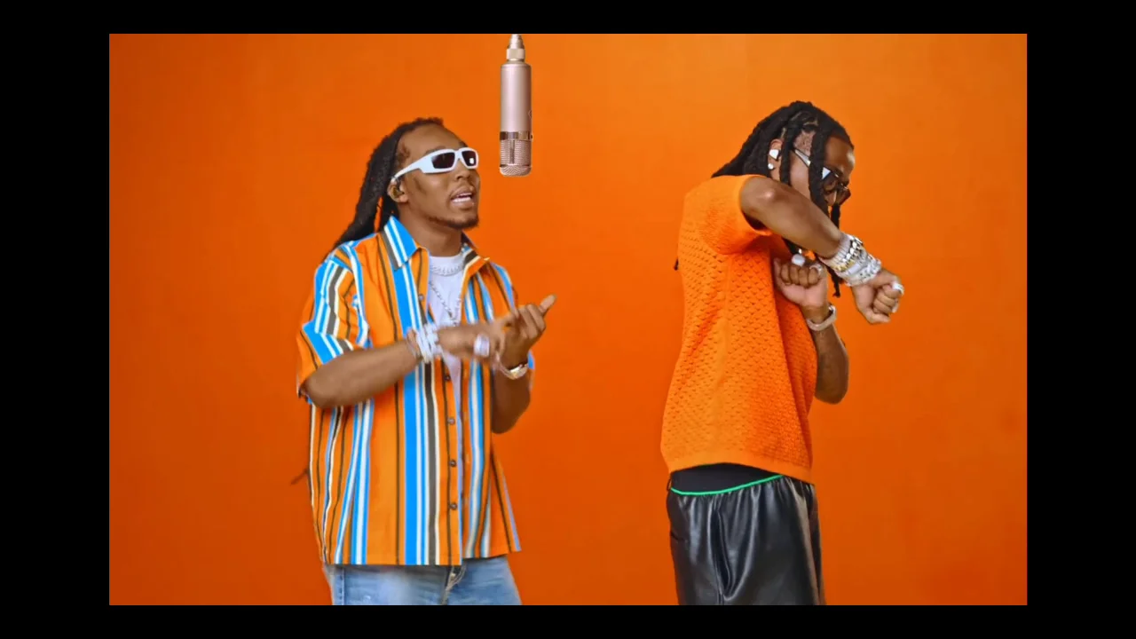 Two performers rapping across the hanging microphone in the orange booth, screenshot from the original video